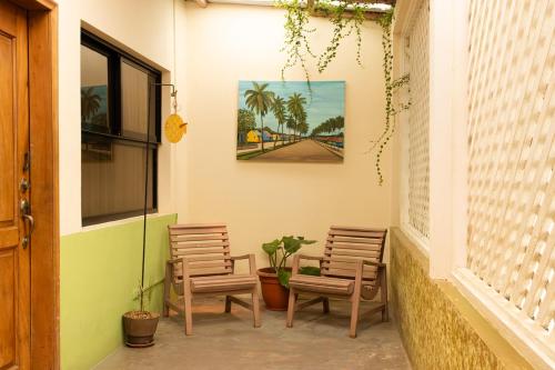 a patio with two chairs and a table and a painting at Hotel Playa Bonita Tela in Tela