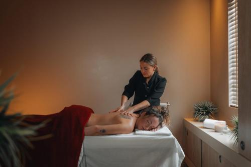 a woman getting a massage from a woman laying on a bed at Hotel Chateau Bromont in Bromont