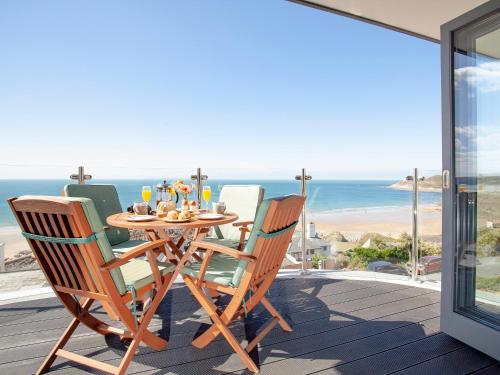 a table and chairs on a deck with a view of the ocean at Soft Sands - Cottage in Woolacombe