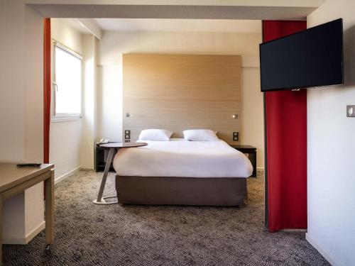 a hotel room with a bed and a flat screen tv at ibis Styles Saint Dizier in Saint-Dizier
