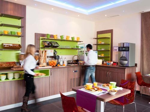 two people standing in a kitchen preparing food at ibis Styles Saint Dizier in Saint-Dizier