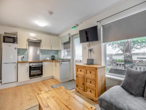 eine Küche mit weißen Geräten und ein Sofa in einem Zimmer in der Unterkunft Arthurs Den - Cottage in Brixham