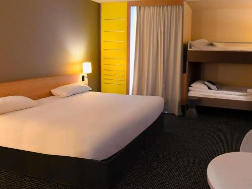 a bedroom with a large white bed and a window at ibis Styles Nantes Reze Aéroport in Rezé