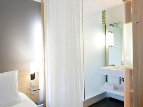 a bathroom with a mirror and a bed and a sink at ibis Styles Nantes Reze Aéroport in Rezé