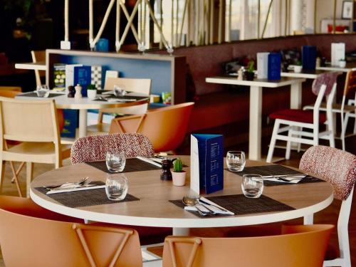 a table in a restaurant with tables and chairs at ibis Styles Nantes Reze Aéroport in Rezé