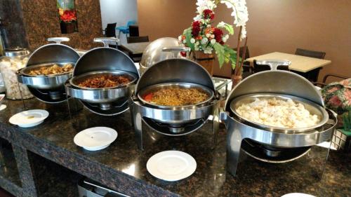 a buffet with severalousand pots of food on a counter at Hotel Ambs Plaza IGI Airport in New Delhi