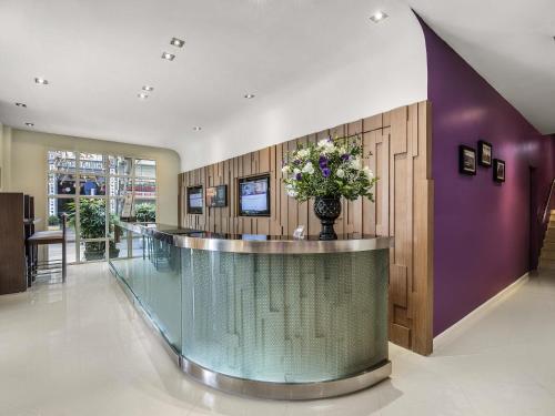 a lobby with a reception counter with a vase of flowers at Mercure Hanoi La Gare Hotel in Hanoi