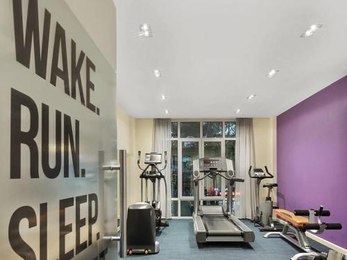 a gym with tread machines and a purple wall at Mercure Hanoi La Gare Hotel in Hanoi