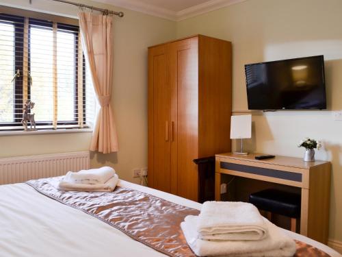 a bedroom with a bed with a desk and a television at Ty Glyndwr in Ystalyfera