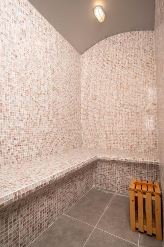 a bathroom with white tile walls and a bench at Iconique Hotel Nha Trang in Nha Trang