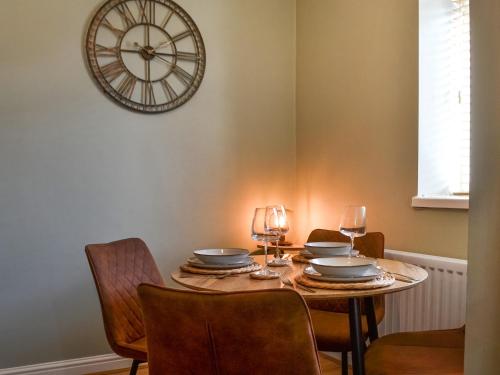 a dining room table with chairs and a clock on the wall at Hogarth Apartment By The Sea-Uk46447 in Newbiggin-by-the-Sea