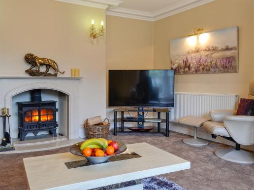 a living room with a television and a fireplace at Maesbangor Farmhouse in Capel Bangor