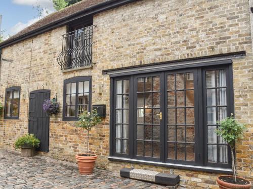 a brick house with black windows and potted plants at The Barn in Chipperfield