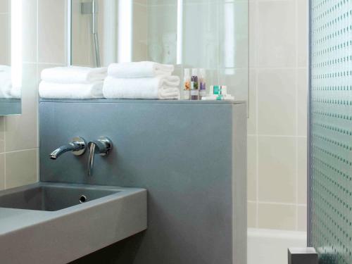 a bathroom with a sink and a mirror and towels at Mercure Amiens Cathédrale in Amiens