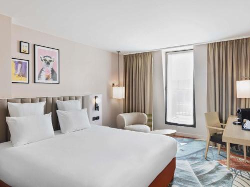 a hotel room with a large white bed and a desk at Mercure Amiens Cathédrale in Amiens