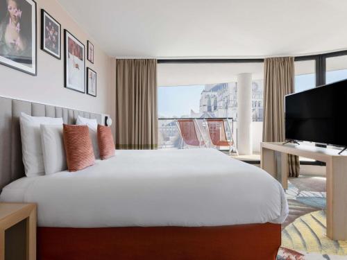 a hotel room with a large bed and a television at Mercure Amiens Cathédrale in Amiens