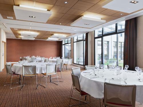 a conference room with white tables and chairs and windows at Mercure Amiens Cathédrale in Amiens