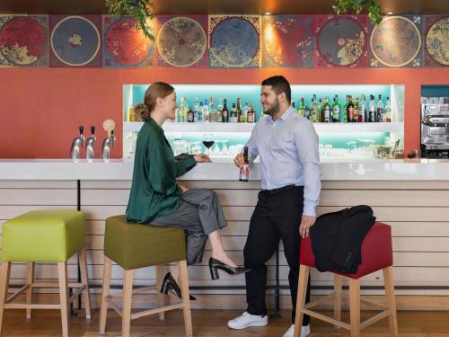 a man and a woman standing at a bar at Mercure Amiens Cathédrale in Amiens