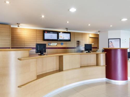 a lobby with a counter with a person in the background at Ibis Aguascalientes Norte in Aguascalientes