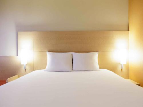 a large white bed with two pillows on it at Ibis Aguascalientes Norte in Aguascalientes