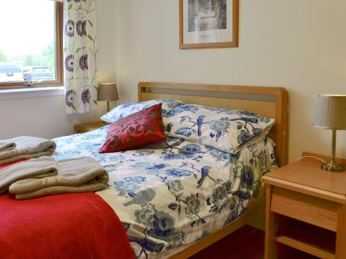 a bedroom with a bed with a blue and white comforter at Carribber Beech in Torphichen