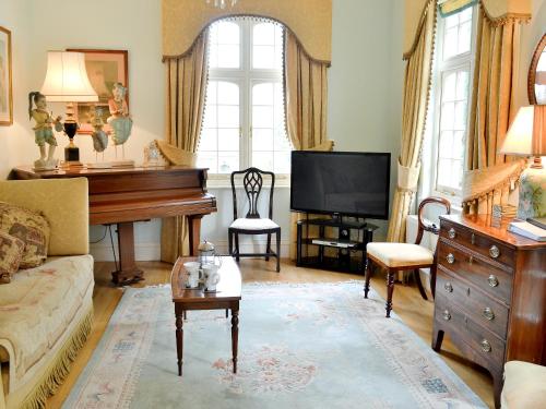 Una sala de estar con un piano y un televisor. en Cutcliffe Chambers - Hppr, en Bideford