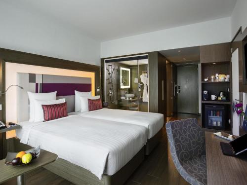 a hotel room with a large bed and a bathroom at Novotel Chennai Sipcot in Chennai