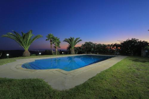 a swimming pool in a yard with palm trees at Luxury Villa 4-Bedroom Estate with Panoramic Tanger Bay Sea View, Private Pool, Garden in Noûnouech