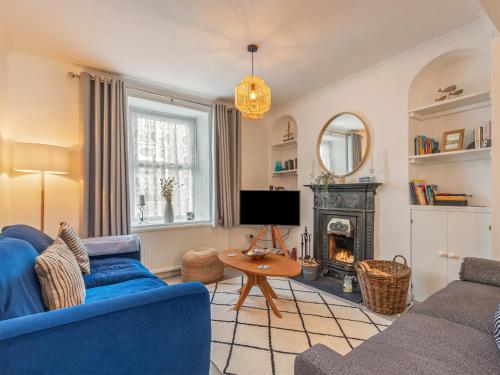 salon z niebieską kanapą i kominkiem w obiekcie Y Ty Glas - Cottage w mieście New Quay