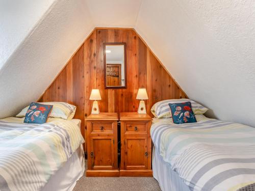 two twin beds in a room with wooden walls at Carraig-Dhubh South - Uk47124 in Whiting Bay