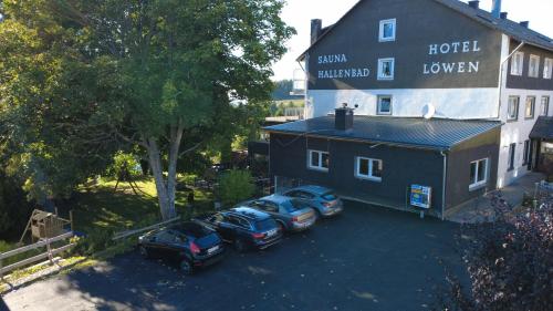three cars parked in a parking lot next to a building at Alpina Löwen Hotel in Sankt Märgen
