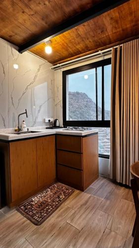 a kitchen with a sink and a large window at كوخ مزرعة قنيف in Al Buhrah
