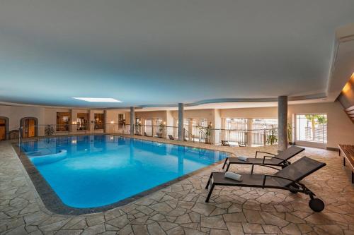 a large pool in a hotel with two lounge chairs and avationliest at Hotel Eller in Solda