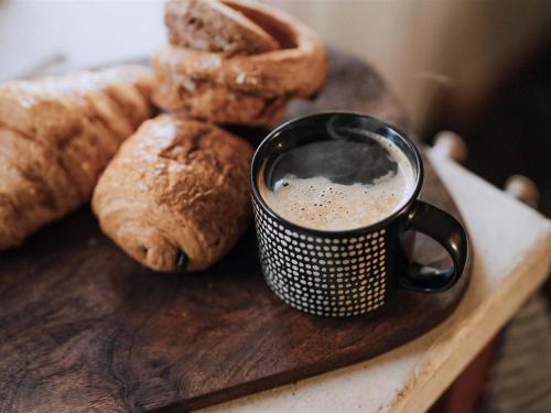 a cup of coffee on a wooden board with bread at The Green One On The End in Thurton