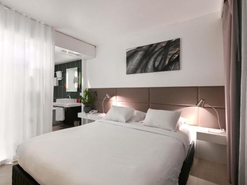 a bedroom with a large white bed with two lamps at Novotel Suites Paris Issy Les Moulineaux in Issy-les-Moulineaux