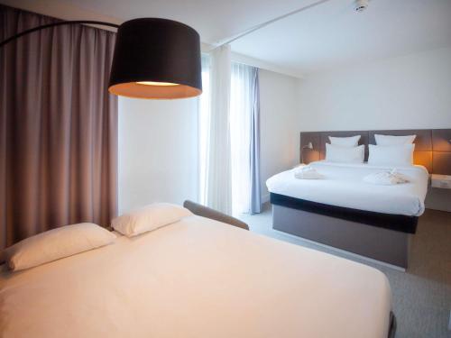 a hotel room with two beds and a large window at Novotel Suites Paris Issy Les Moulineaux in Issy-les-Moulineaux