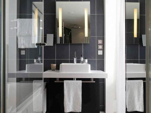 a bathroom with two sinks and a mirror at Novotel Suites Paris Issy Les Moulineaux in Issy-les-Moulineaux