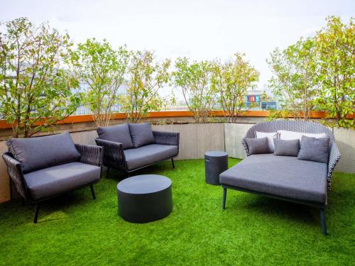 a patio with three chairs and a table and grass at Novotel Suites Paris Issy Les Moulineaux in Issy-les-Moulineaux