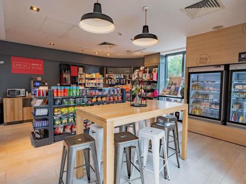 a restaurant with a table and stools in a store at Novotel Suites Paris Issy Les Moulineaux in Issy-les-Moulineaux