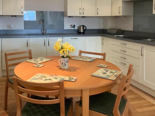 a kitchen with a wooden table with a vase of flowers on it at Woodside Cottage in Troutbeck Bridge