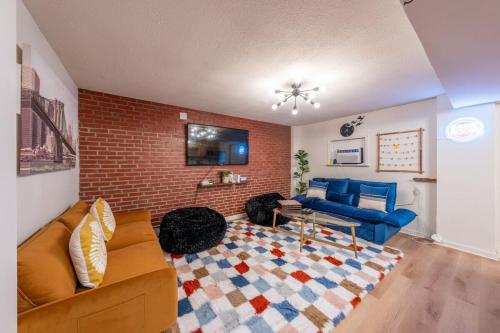 a living room with a couch and a brick wall at 5BR 3BTH House, Steps to Bars, Dining, NYC Access with GameRm, Backyard with BBQ and Parking in Jersey City
