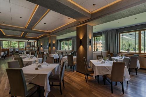 a restaurant with white tables and chairs and windows at Hotel Eller in Solda