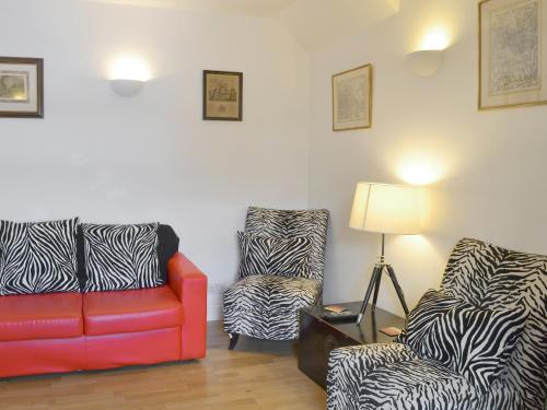 ein Wohnzimmer mit 2 Stühlen und einem roten Sofa in der Unterkunft Checkers Cottage - Beaufort Estate in Belladrum