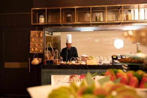 a man in a chefs hat standing in a kitchen at Iconique Hotel Nha Trang in Nha Trang