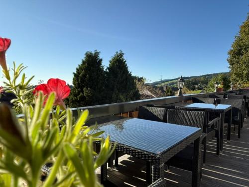 a row of tables and chairs on a deck with flowers at Alpina Löwen Hotel in Sankt Märgen