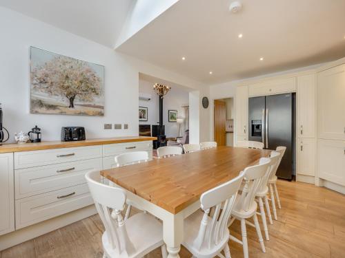 a kitchen with a wooden table and white chairs at Amaranth in Shurdington