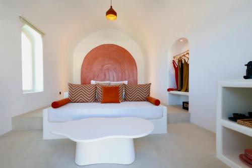 a room with a white couch with pillows at Bluewhite Suites & Villa Santorini in Pirgos