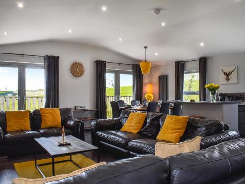 a living room with black leather furniture and yellow pillows at The Barbon - Uk47033 in Kirkby Lonsdale