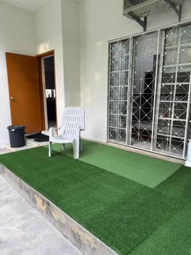 a white chair sitting on a green carpet at Lake House Sepang88 in Sepang