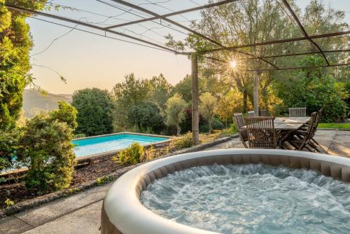an outdoor hot tub with a pergola next to a pool at Portugal Active São Julião Retreat | Pool, Jacuzzi & Garden Escape in Mato
